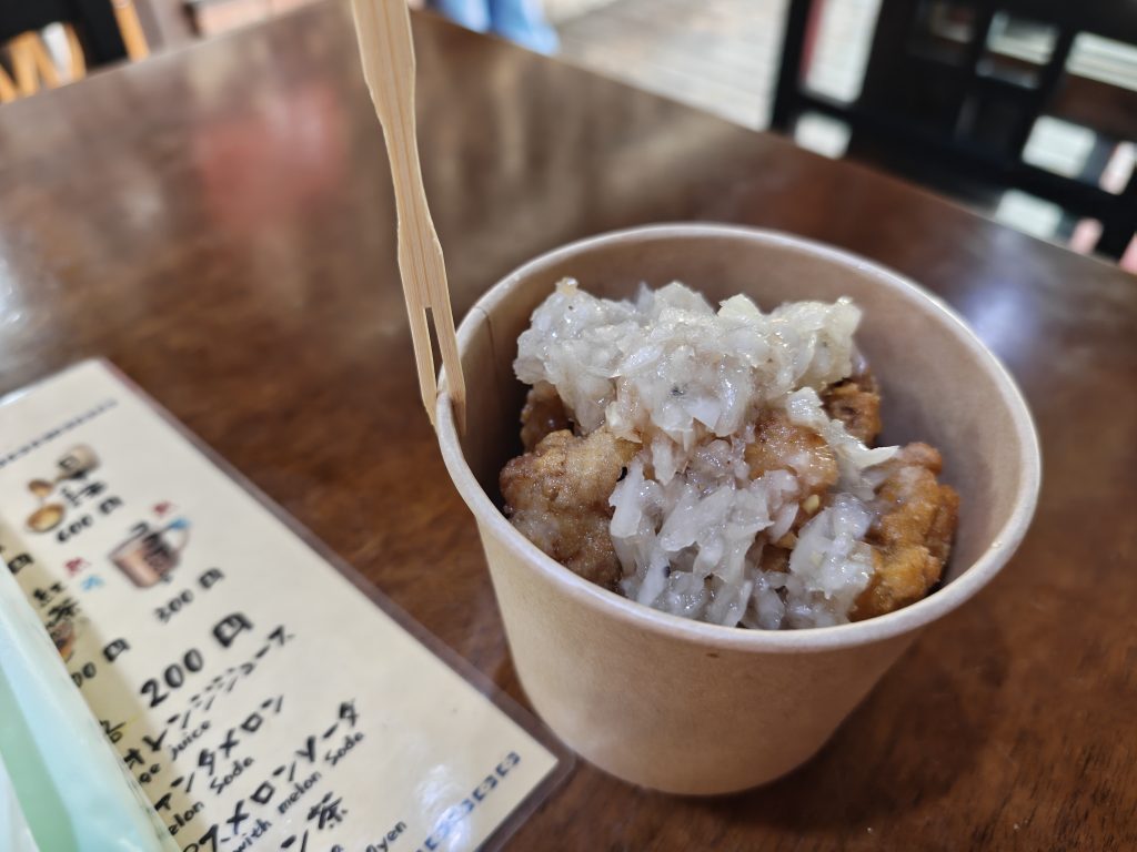 Un plat de karaage, du poulet frit japonais, servi avec des oignons émincés dans un récipient en carton.
