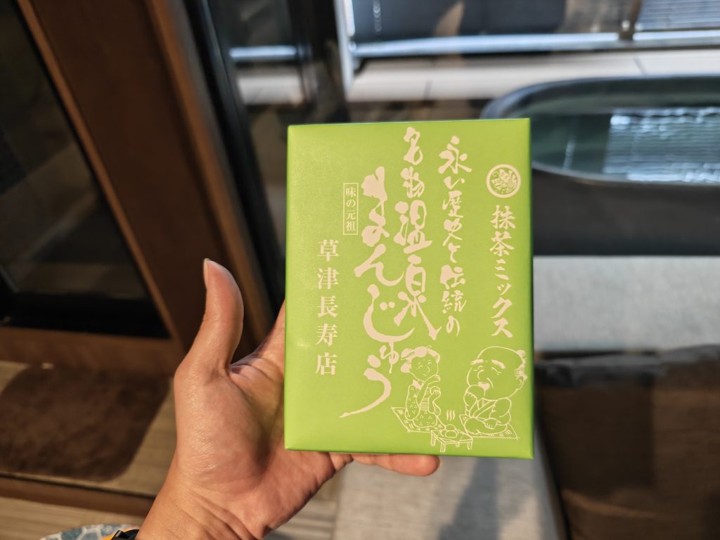 Boîte de sucreries vertes au matcha, tenue dans une main, avec des illustrations et des inscriptions japonaises.